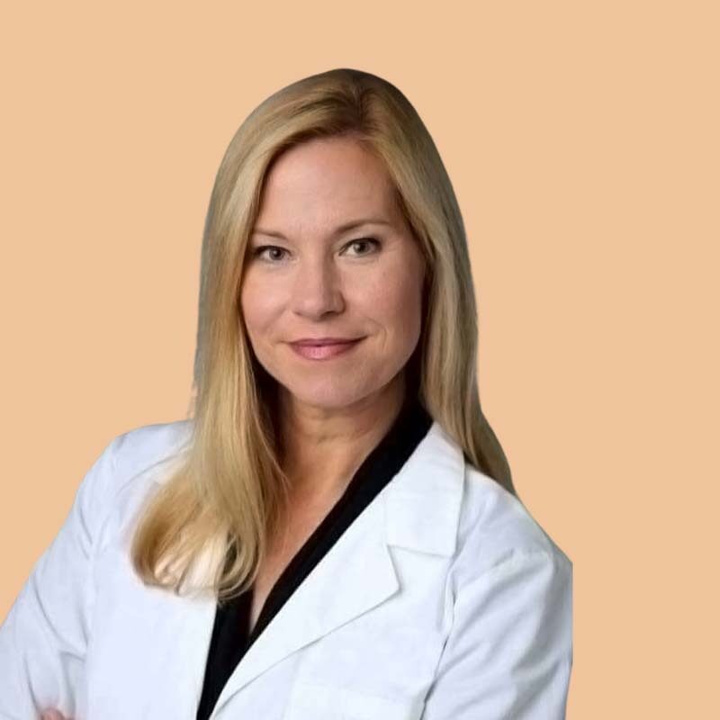 A woman with long blond hair in a white coat poses against a plain background.