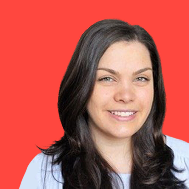 A person with long dark hair smiles at the camera against a bright red background.